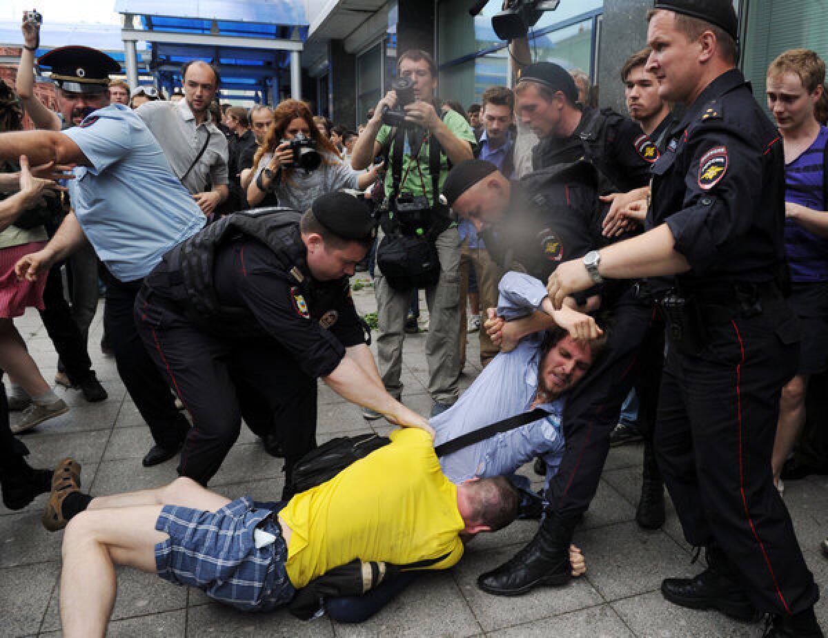 Russian police officers separate a protester and a gay rights activist clashing outside the lower house of parliament in Moscow.
