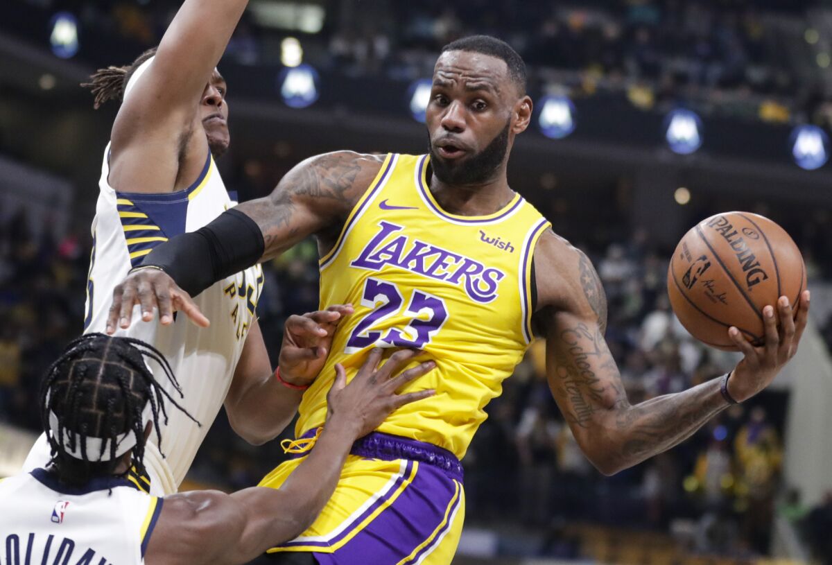 Lakers forward LeBron James passes in front of Indiana Pacers guard Aaron Holiday and center Myles Turner.