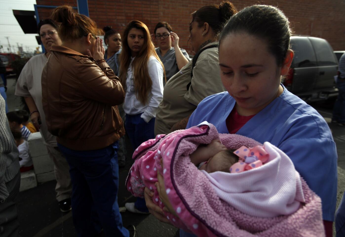 Yessica Ceja holds her 2-month-old daughter, Delaney Dominguez, as she stands with other students in front of Career Colleges of America's South Gate campus Thursday. She enrolled at the school nearly two years ago, she said, because "I wanted a better future to support my family financially." She owes nearly $20,000 in loans now.