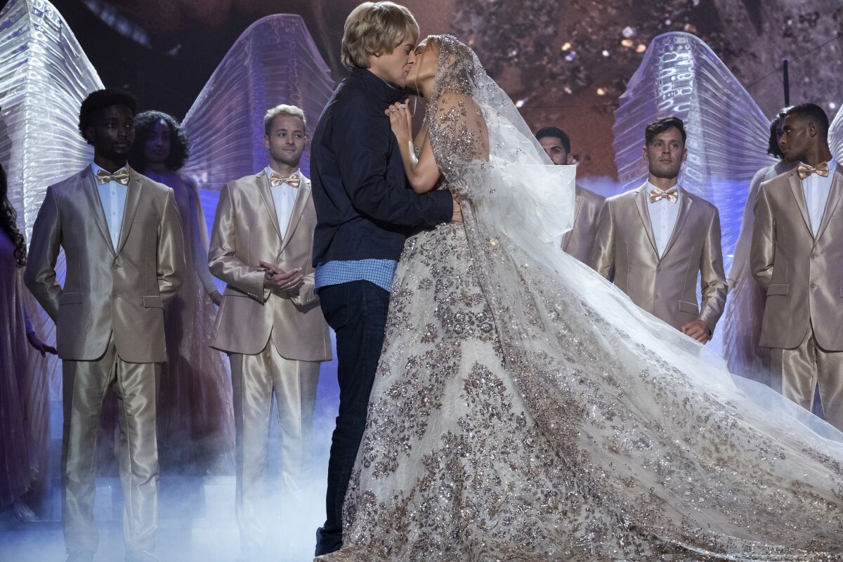 Owen Wilson , in casual street clothes, and Jennifer Lopez, in a wedding veil and dress, kiss in scene from “Marry Me”