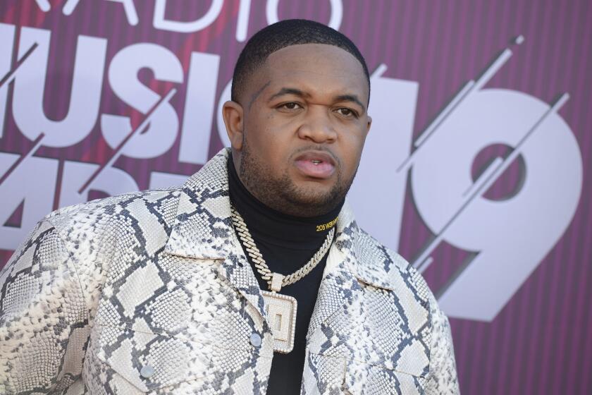 DJ Mustard in a snakeskin jacket, black turtleneck and a large chain