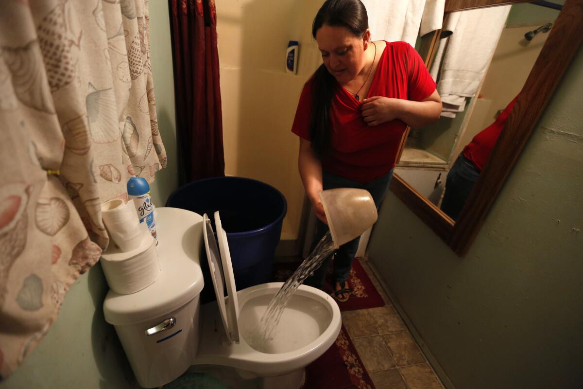 In East Porterville, Guillermina Andrade must pour water into a toilet for it to flush.