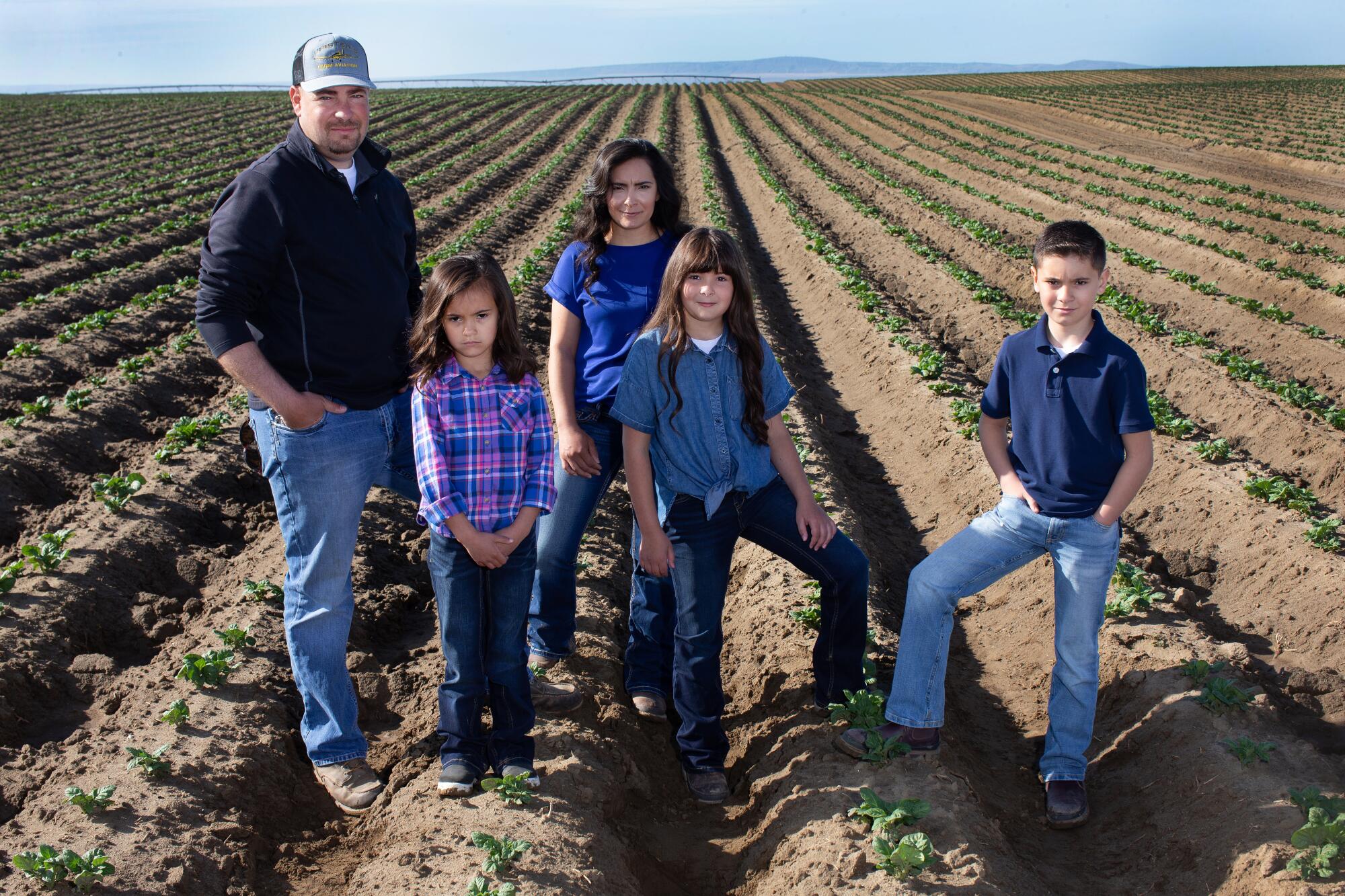 Jordan Reed, left, and his wife, Mia, third from left, own JM Farms. Here they pose with children Breanna, 5, Addison, 8, and Owen, 10, in a neighbor's potato field in Pasco, Wash.