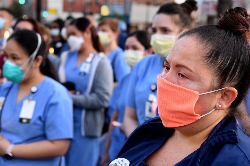 LOS ANGELES, CALIFORNIA MAY 6, 2020-Monique Hernandez, a registered nurse for Riverside Community Hospital, attends a candlelight vigil for nurse Celia Marcos outside Hollywood Presbyterian Medical Center in Los Angeles Wednesday. Marco died from the coronavirus. (Wally Skalij/Los Angeles Times)