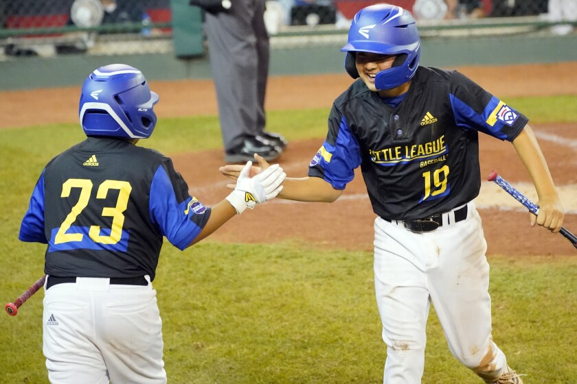 Gibson Turner de Torrance Little League célèbre avec Christian Chavez après avoir marqué sur un coup sûr.