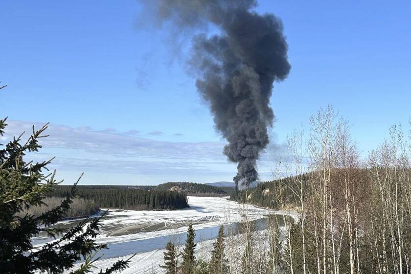 FILE - Smoke rises after a Douglas C-54 Skymaster plane crashed into the Tanana River outside Fairbanks, Alaska, Tuesday, April 23, 2024. A witness who saw the vintage military plane loaded with fuel for delivery shortly after it took off from an airport in Fairbanks, last week said the far-left engine of the aircraft was not running but trailing a small, white plume of smoke, according to a preliminary crash report released Thursday, May 2. (Gary Contento via AP, File)