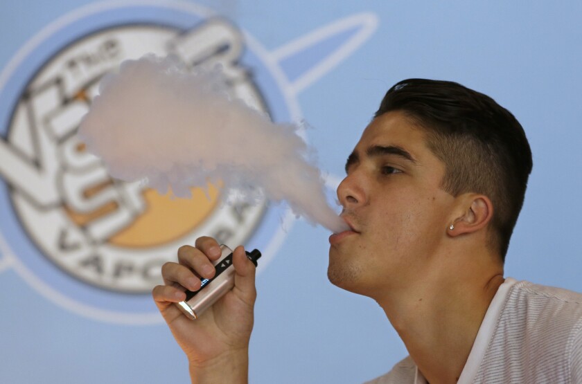 A 19-year-old exhales vapor from an e-cigarette at the Vapor Spot in Sacramento on July 7.