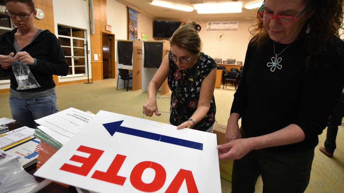 Poll workers set up a voting station at Laguna Beach City Hall in 2018. The Orange County registrar of voters office is hiring employees to staff its new voting centers for upcoming elections.