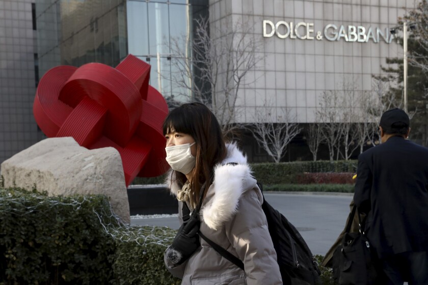 FILE - In this Nov. 25, 2018 file photo, a woman walks past a Dolce&Gabbana retail outlet in Beijing, China. The Milan fashion house Dolce&Gabbana filed a multi-million-dollar defamation suit in an Italian court against U.S. fashion bloggers who reposted anti-Asian comments attributed to one of the designers that led to a boycott by Asian consumers. The suit was filed in Milan civil court in 2019, but only became public this week, Thursday, March 4, 2021, when the bloggers posted about it on their Instagram profile, Diet Prada. (AP Photo/Ng Han Guan, file)