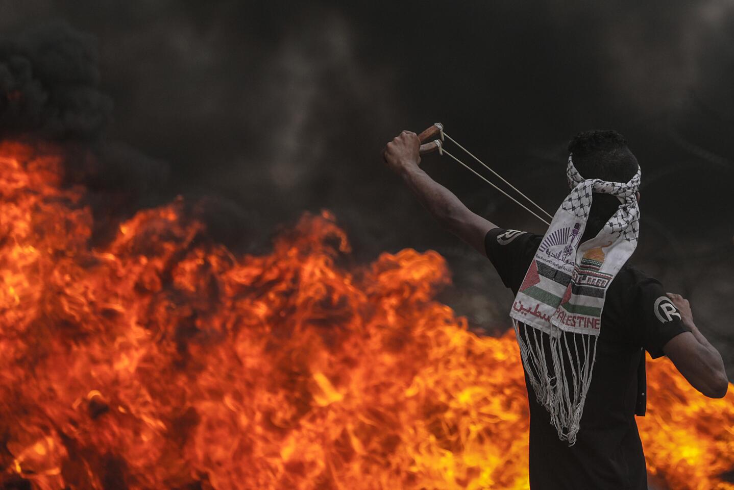 A Palestinian protester throws stones with a slingshot during clahses after protests near the border with Israel in Gaza City on May 4, 2018.