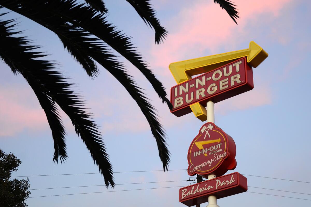 In-N-Out Burger's Baldwin Park sign against a dusk sky and a partial silhouette of a palm tree.