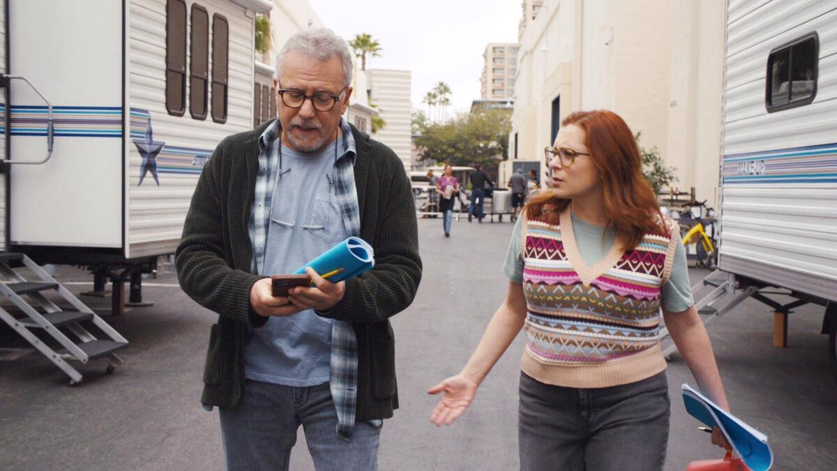 A man and a woman walk and talk in a scene from the TV series"Reboot."