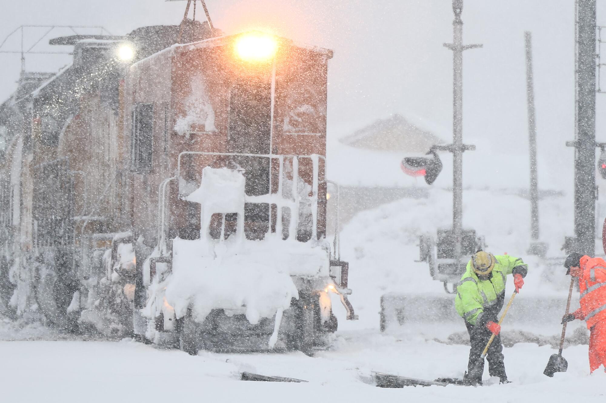 Workers clear train tracks as snow falls during a powerful winter storm.