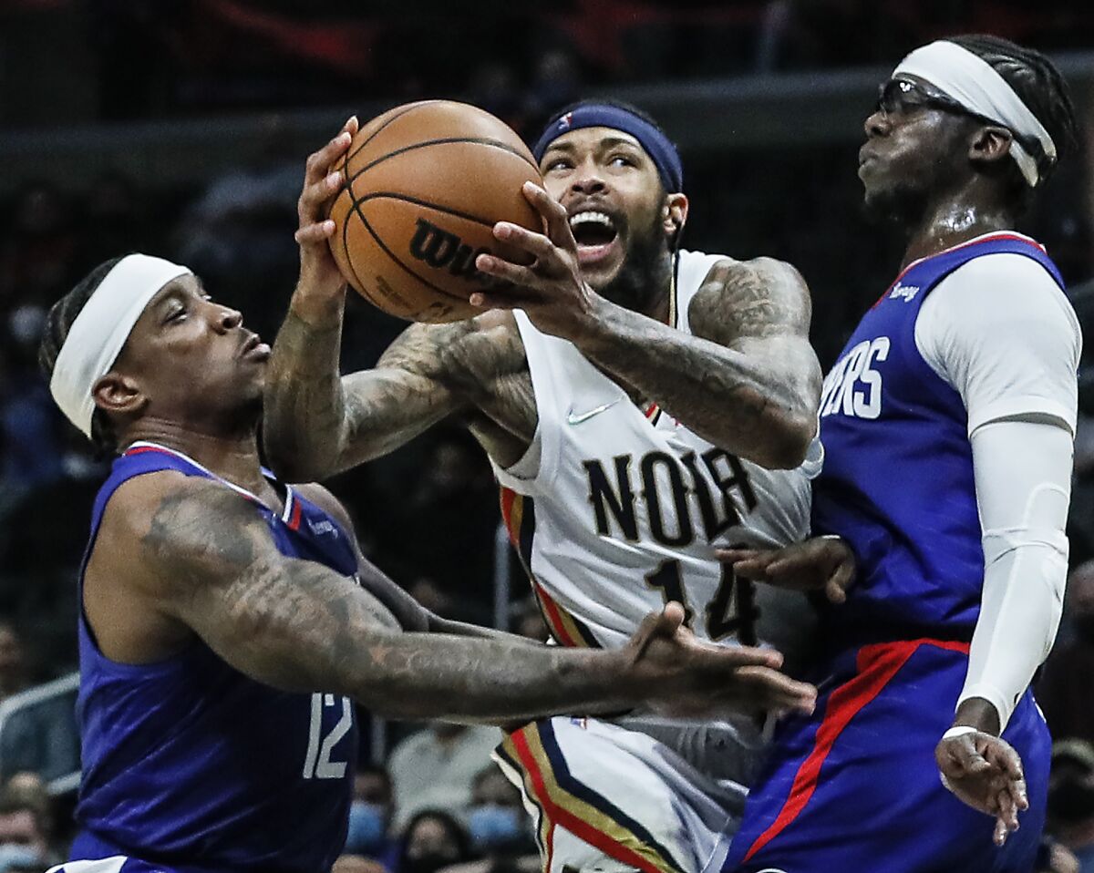 New Orleans Pelicans forward Brandon Ingram struggles to shoot over Clippers guard Eric Bledsoe and guard Reggie Jackson.
