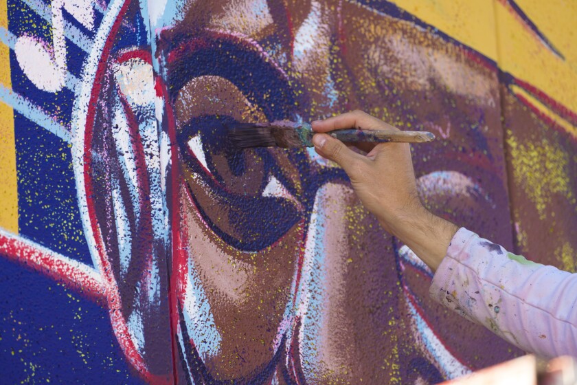 Artist Taylor Gallegos works on a mural in East Village honoring Makeda