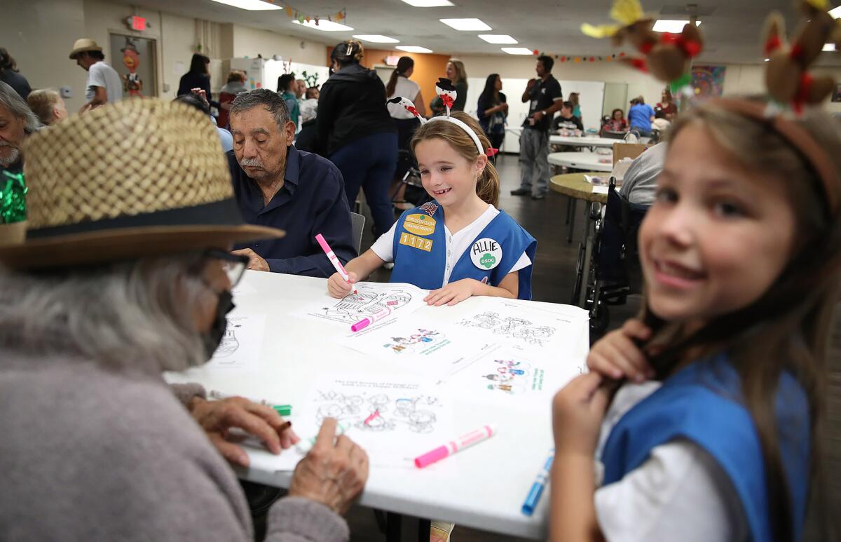 Members of Girl Scouts troop 1172 help seniors color holiday illustrations.