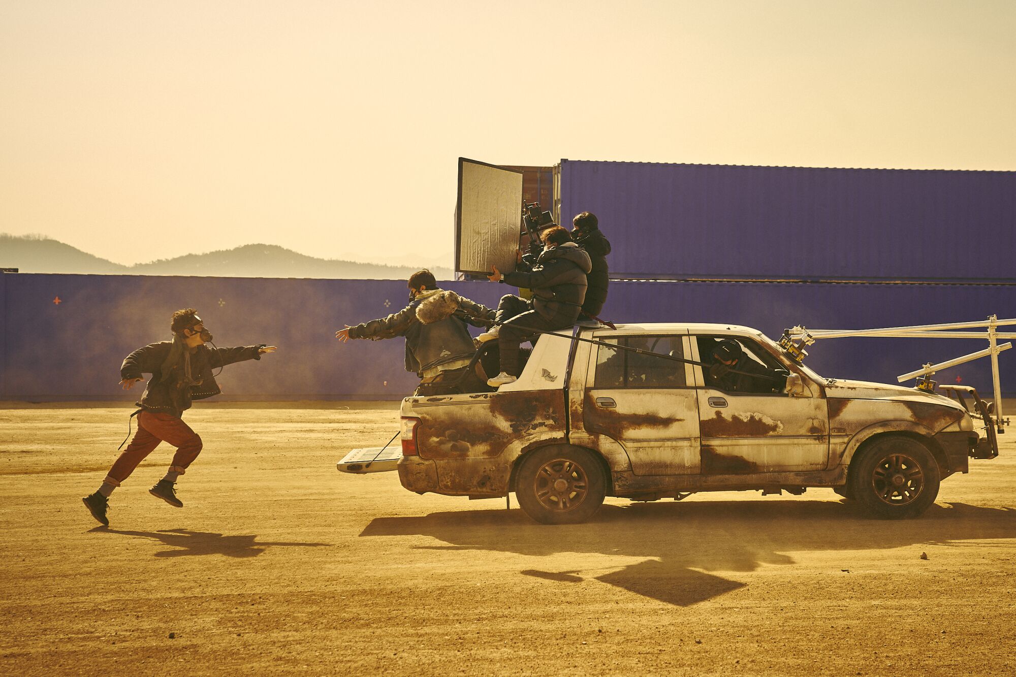 A man on a vehicle reaches his arm out to another man chasing the vehicle in foot 