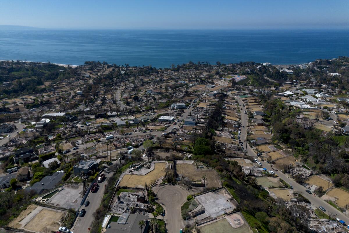 An aerial view of homes destroyed by fire, with the ocean as a backdrop