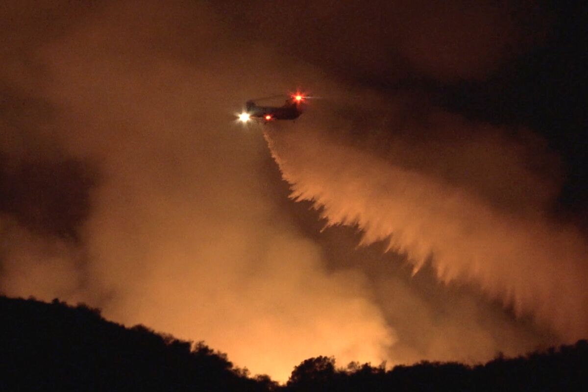 A helicopter makes a night drop on a fire in Malibu.