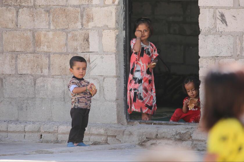 Syrian children stand in front of a house in the Kurdish-majority northeastern city of Qamishli.