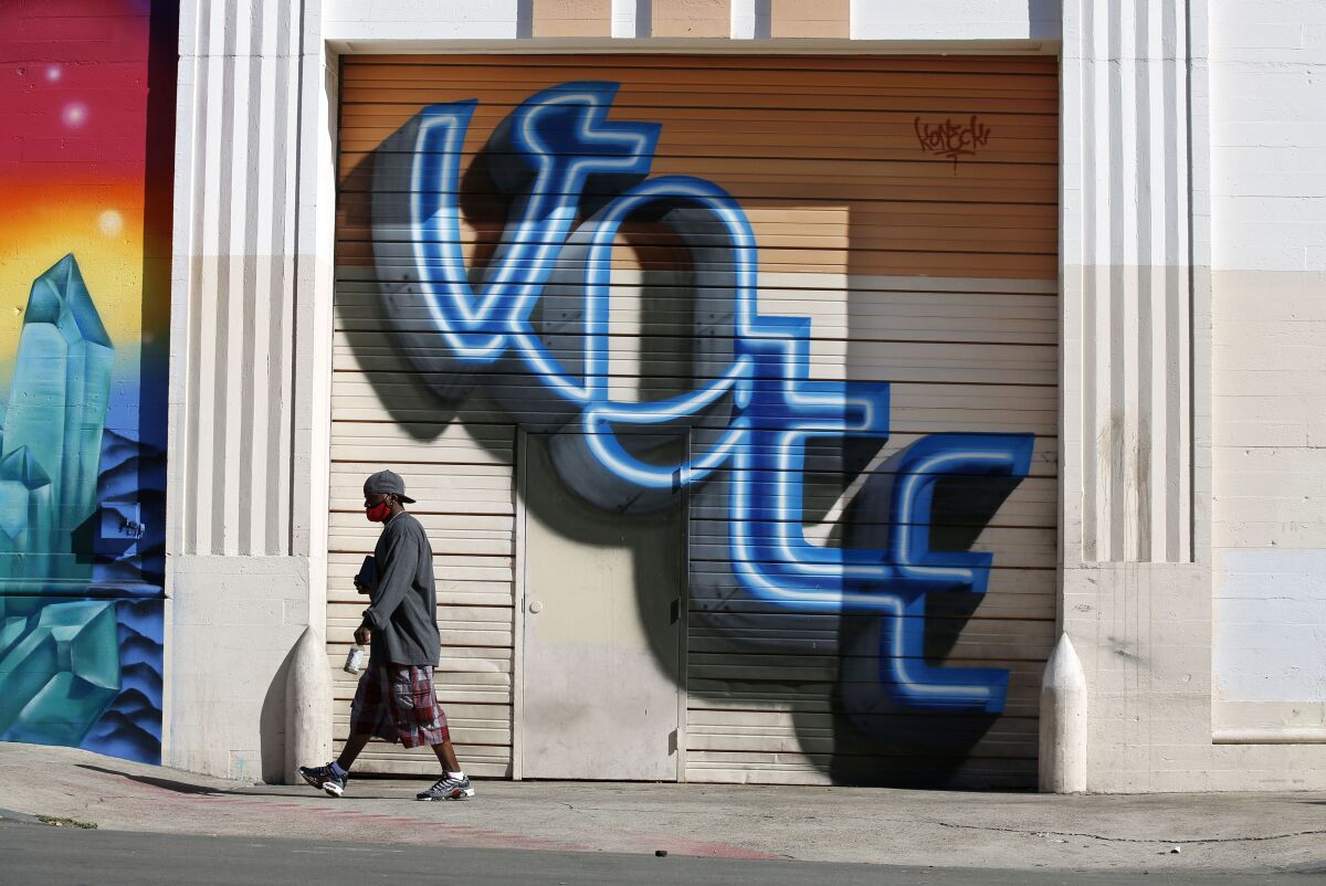 A person walks by a "Vote" mural on 9th Ave in downtown San Diego on Monday.