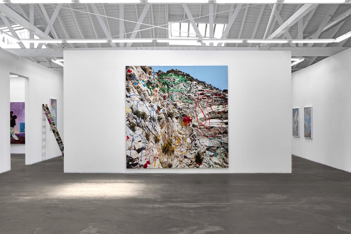 A large colorful painting hands on a white gallery wall.