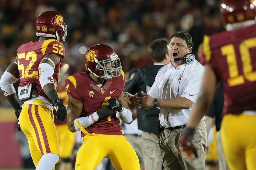 USC Interim Coach Ed Orgeron celebrates with cornerback Torin Harris, center, after the Trojans blocked a Stanford field-goal attempt in the second half of USC's 20-17 win Saturday.