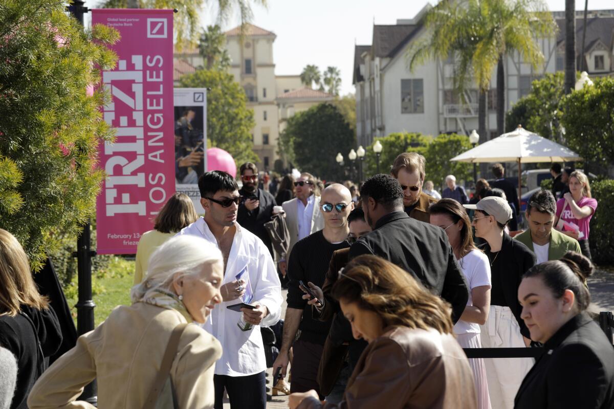 People stream past a banner that reads "Frieze Los Angeles."  