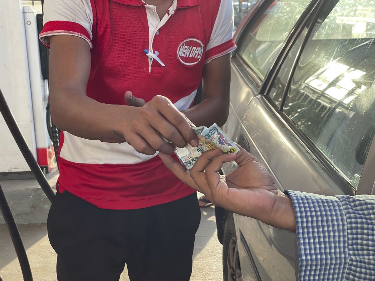 A driver hands over Myanmar kyats to an attendant as payment for fuel at a gas station in Botahtaung township in Yangon, Myanmar on Nov. 12, 2021. The military takeover in Myanmar has set its economy back years, if not decades, as political unrest and violence disrupt banking, trade and livelihoods and millions slide deeper into poverty. (AP Photo)