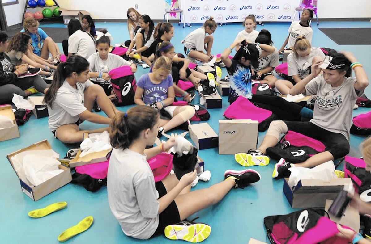 Girls of South Lake Middle School in Irvine get their hands on running shoes from Asics, an athletic equipment company and partner to national organization Girls on the Run.