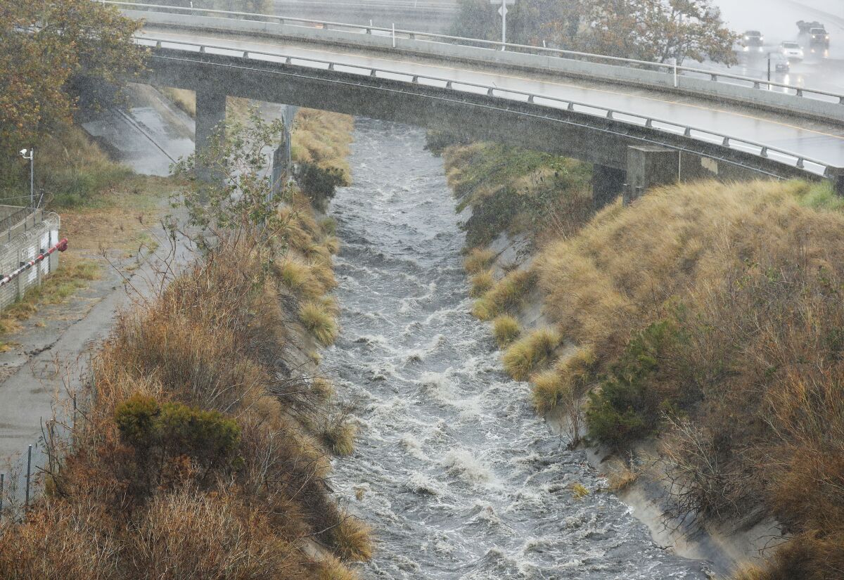 Water flows down a flood control channel along I-15 in Mission Valley where lifeguards rescued a man and woman Tuesday