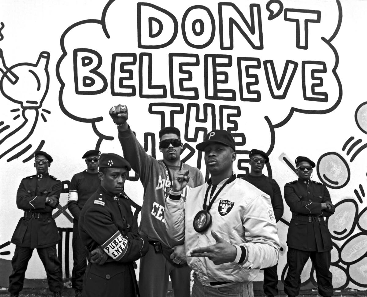 Black and white photo of seven men, the one in the middle raising his fist 