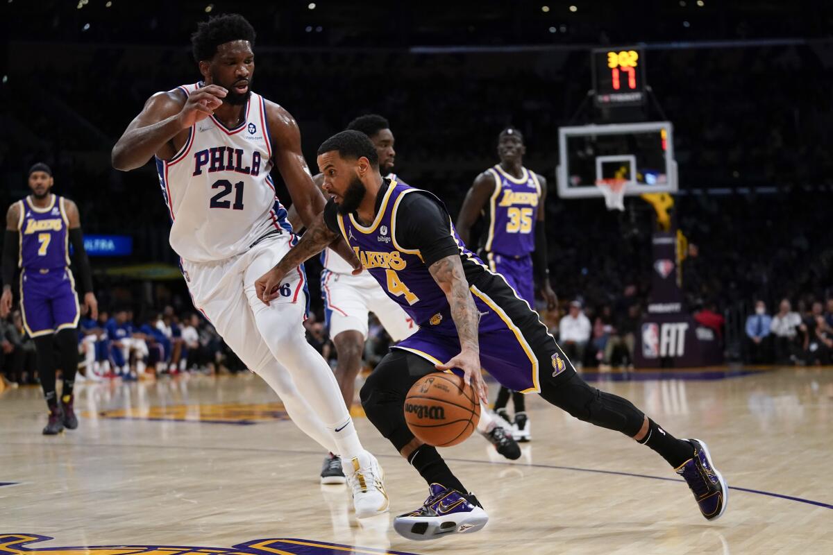 Philadelphia 76ers center Joel Embiid defends against Lakers guard D.J. Augustin.