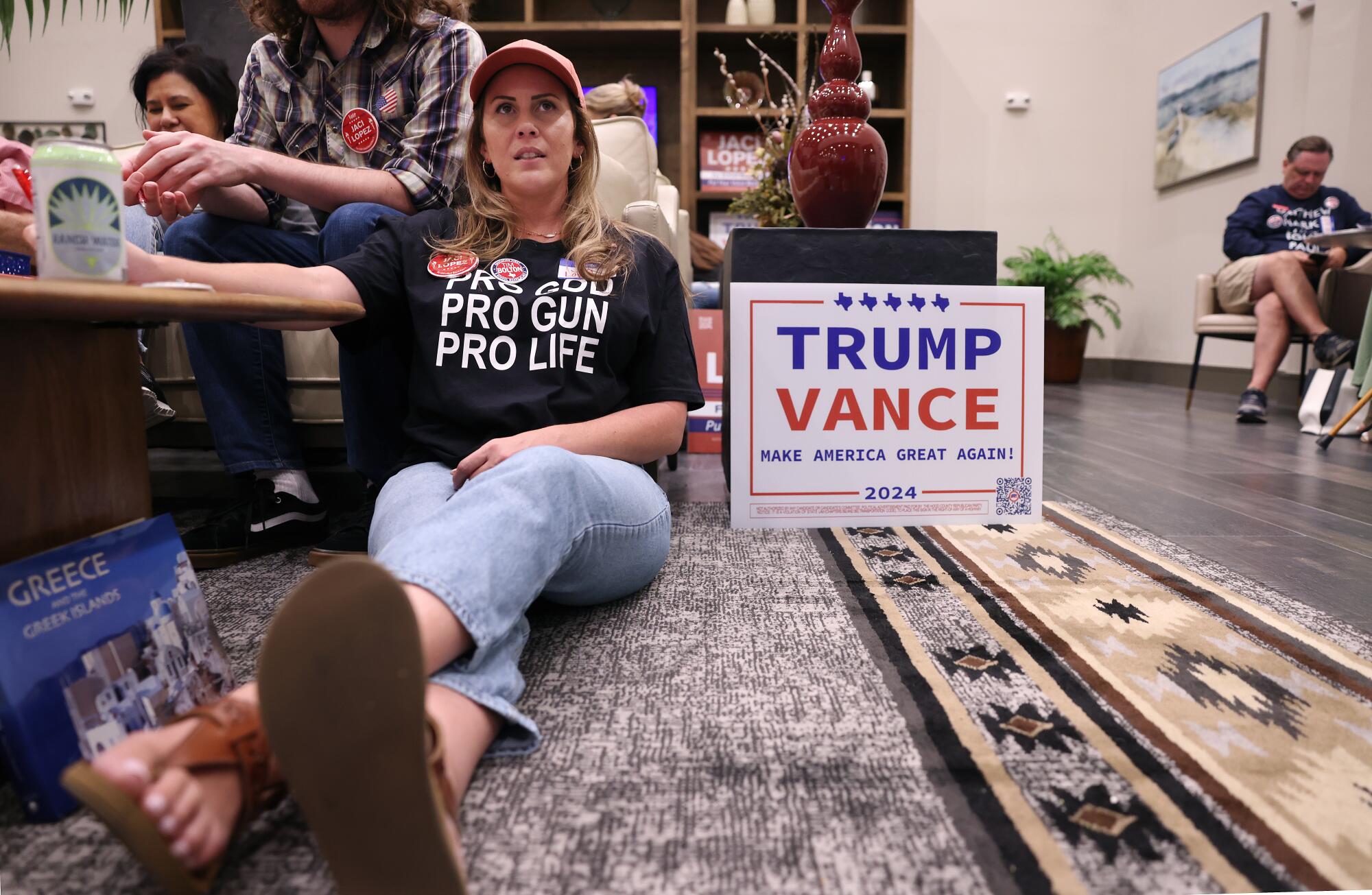 A woman sits on the floor with people behind her on a couch