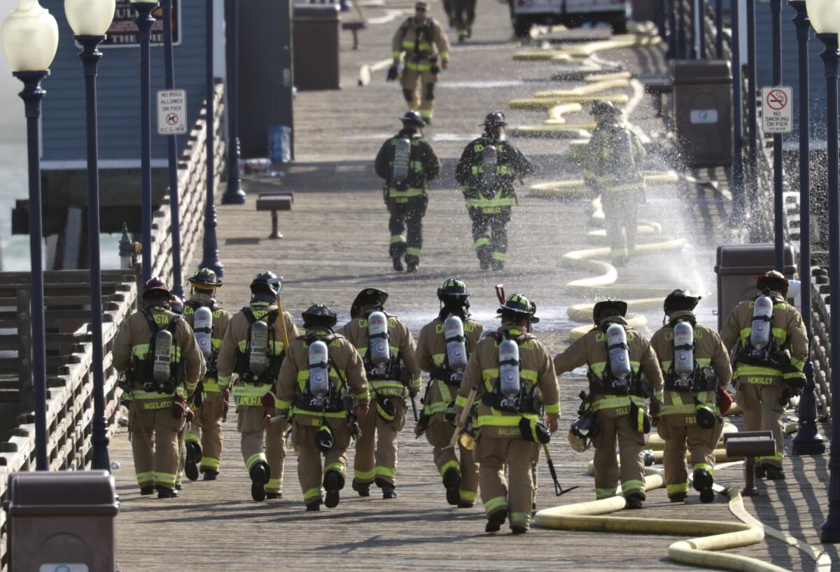 Firefighters walk toward a fire at the end of the Oceanside Municipal Pier on April 25.