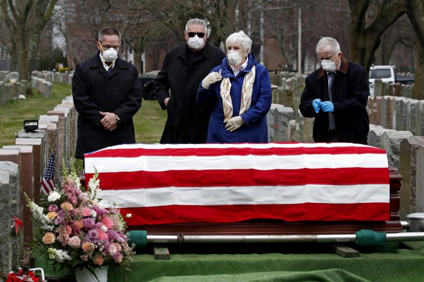 Mourners stand by the casket of veteran Mary Foley, Wednesday, April 8, 2020, in Malden, Mass. Foley, who died at the age of 93, served in the U.S. Air Force, including WWII. Due to the coronavirus crisis, she cannot be given a formal military funeral. (AP Photo/Elise Amendola)