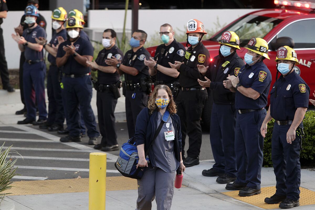 Erica Fitzgibons, a nurse practitioner at Dignity Health Glendale Memorial Hospital, smiles as she arrives to work on Thursday as members of the Glendale fire and police departments cheer on health-care workers dealing with the coronavirus pandemic. 