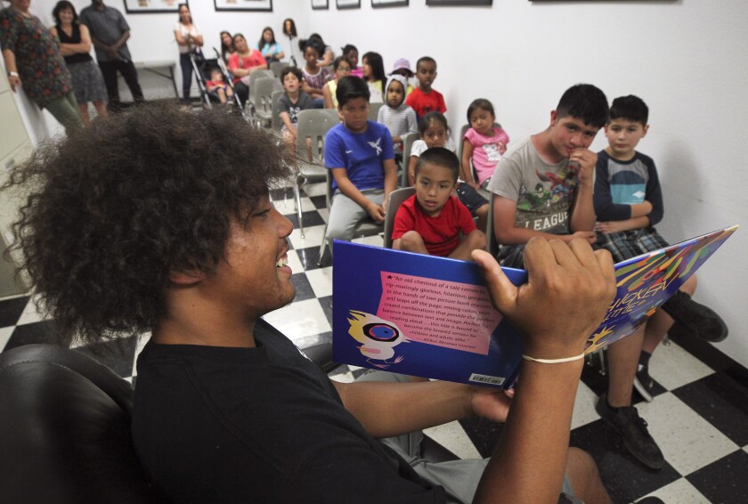 Jerry Riggins Jr., 16, is a son of the owner of Riggins Urban Barber College. Here he reads "Chicken Little" to children during Summer Time is Reading Time in the Diamond, a children's book read-aloud, at the barber school on Wednesday, July 10 in San Diego.