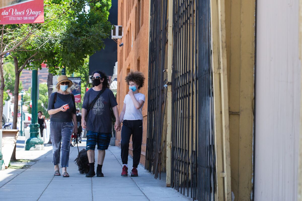 Masked pedestrians walk their dog in Little Italy on July 3, 2020.