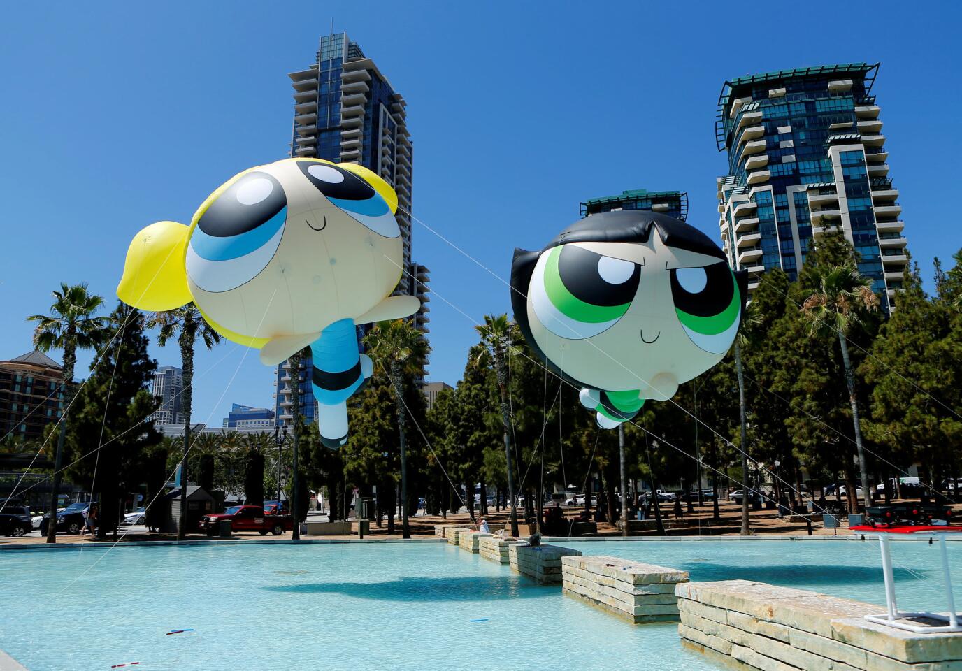 Helium-filled Powerpuff Girls figures float over a fountain as they are installed for the start of Comic-Con International in San Diego, California