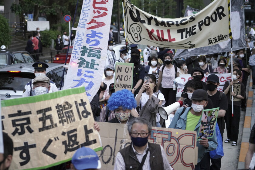 Protesters hold anti-Olympic signs in Japanese and English.