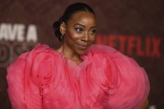 Erica Ash smiles while wearing a voluminous, ruffled pink gown