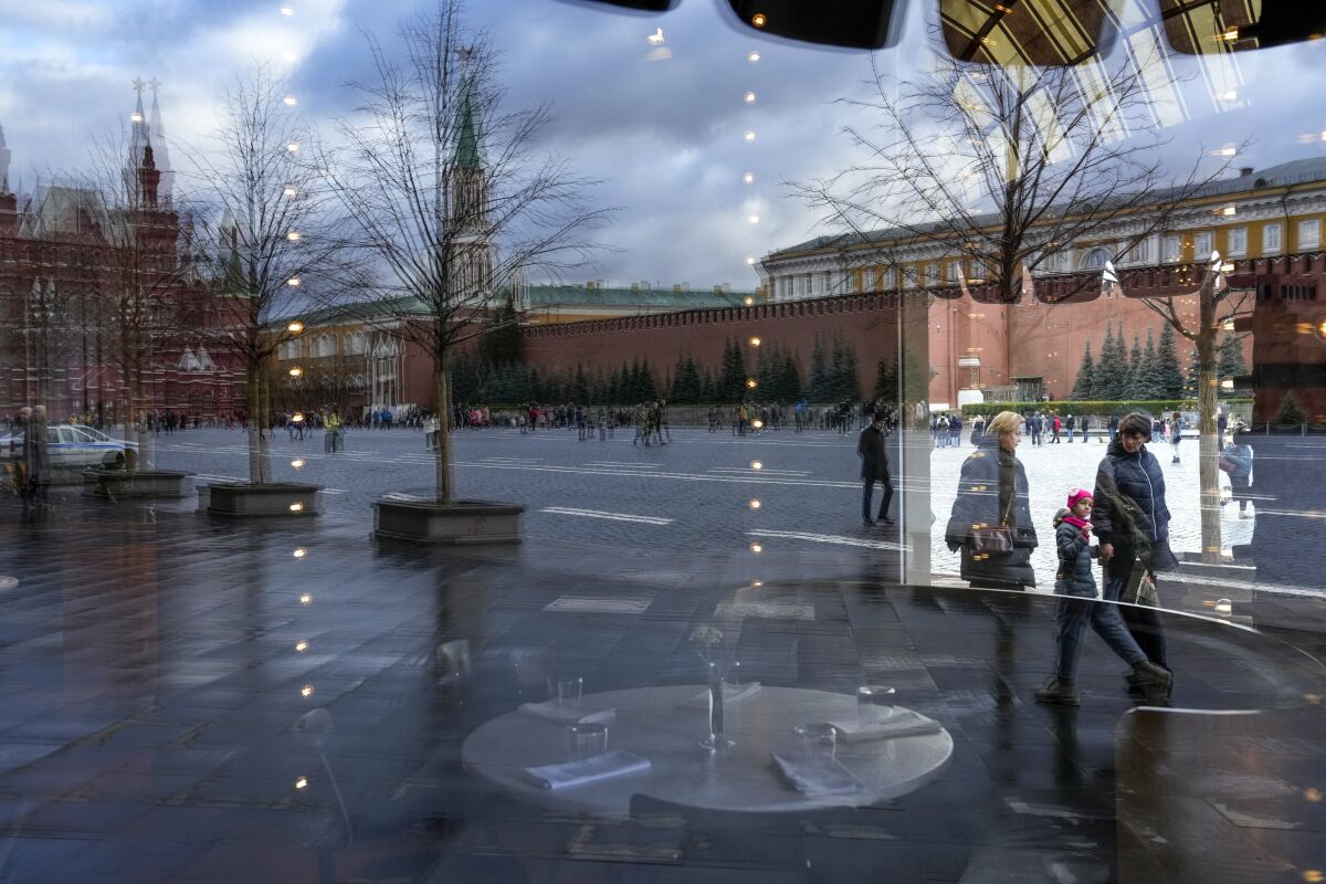 Red Square and the Kremlin Wall are reflected in a window of an empty BOSCO cafe in the GUM, the State Shop in Red Square, which is closed due to COVID-19 in Moscow, Russia, Thursday, Oct. 28, 2021. Moscow followed Thursday, shutting kindergartens, schools, gyms, entertainment venues and most stores, and allowing restaurants and cafes to only provide service for takeout or delivery. The number of new daily cases in Russia rose by over forty thousand on Thursday, topping a previous record reached earlier this week. The government hopes that the nonworking period will help curb the spread by keeping most people out of offices and public transportation. (AP Photo/Alexander Zemlianichenko)