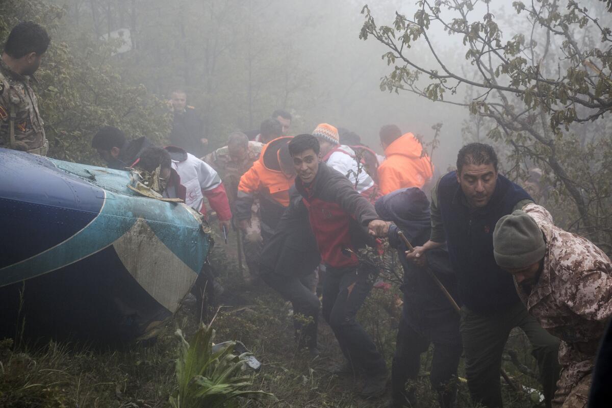 Rescue team members work in fog at the scene of a crash of a helicopter carrying Iranian President Ebrahim Raisi.