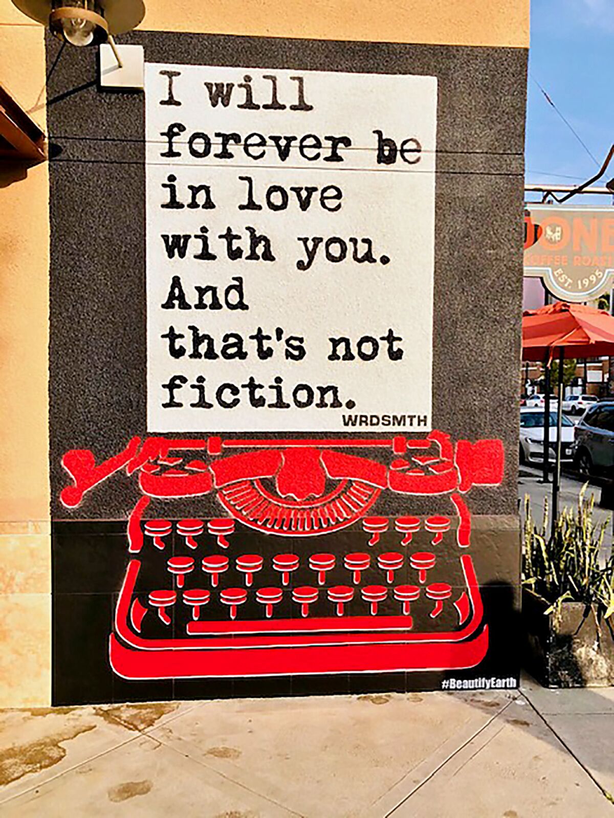 A mural of a red typewriter and piece of paper with the words "I will forever be in love with you. And that's not fiction."