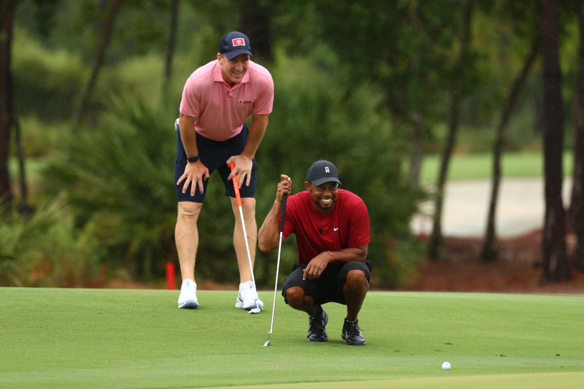 Peyton Manning and Tiger Woods line up a putt on the green.