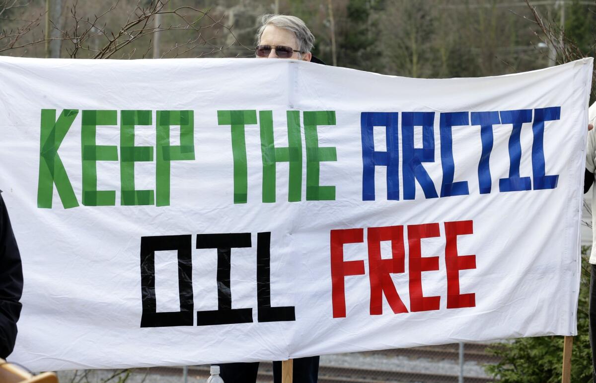 A demonstrator peers over a protest sign during a press conference in Seattle Jan. 28. Several environmental and political groups called the gathering to voice their opposition to a plan for Royal Dutch Shell PLC to use Seattle's waterfront as a winter homeport for its Arctic drilling fleet.