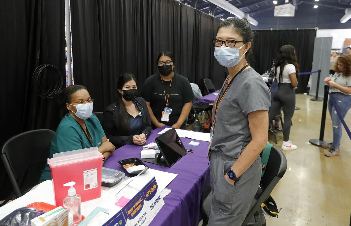 Maxim Healthcare Services site manager Karen Hsu, right, stand at the OC Fair awaiting walk-up guests who want a vaccine.