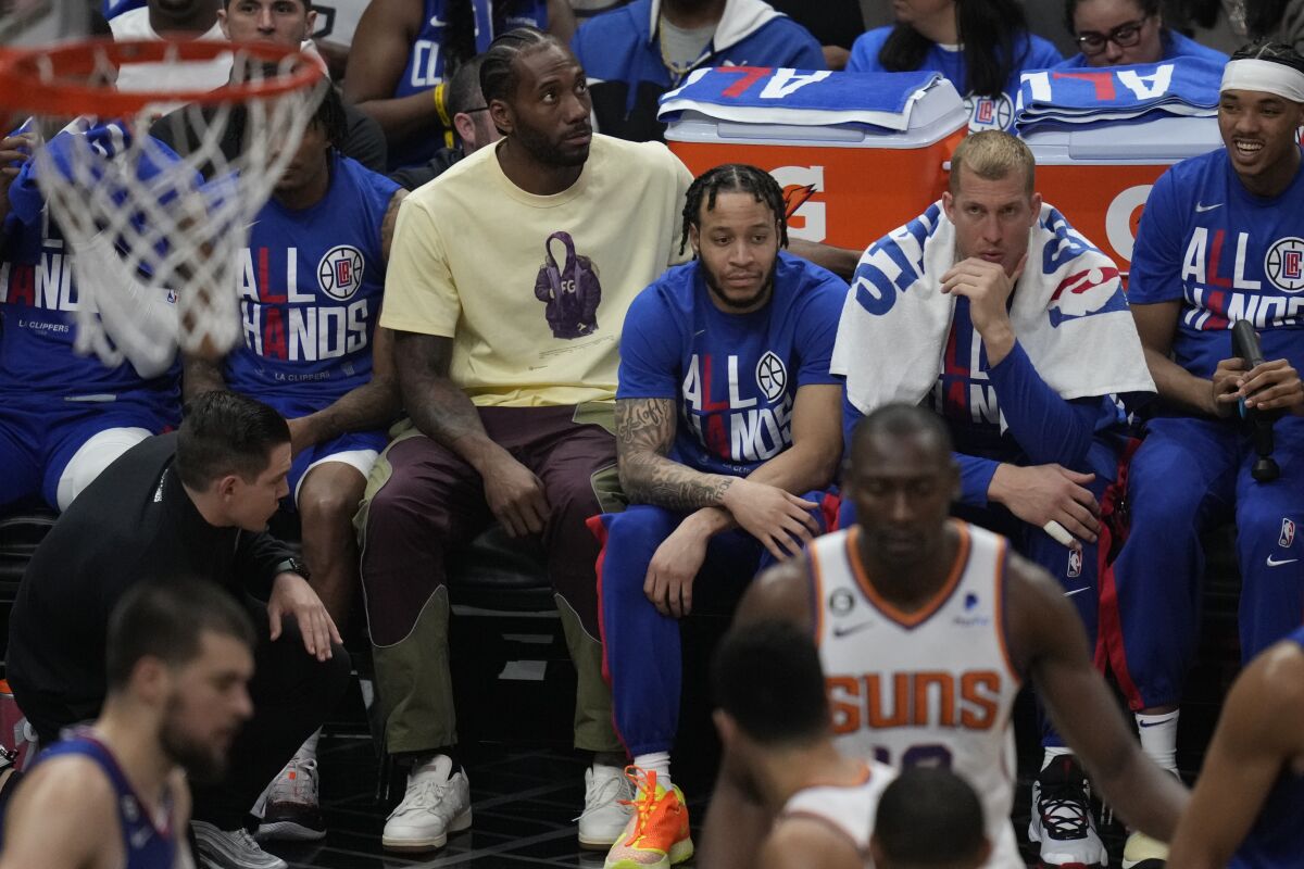 Kawhi Leonard, en jaune, est assis sur le banc des Clippers lors du match 3 contre les Phoenix Suns le 20 avril à la Crypto.com Arena.