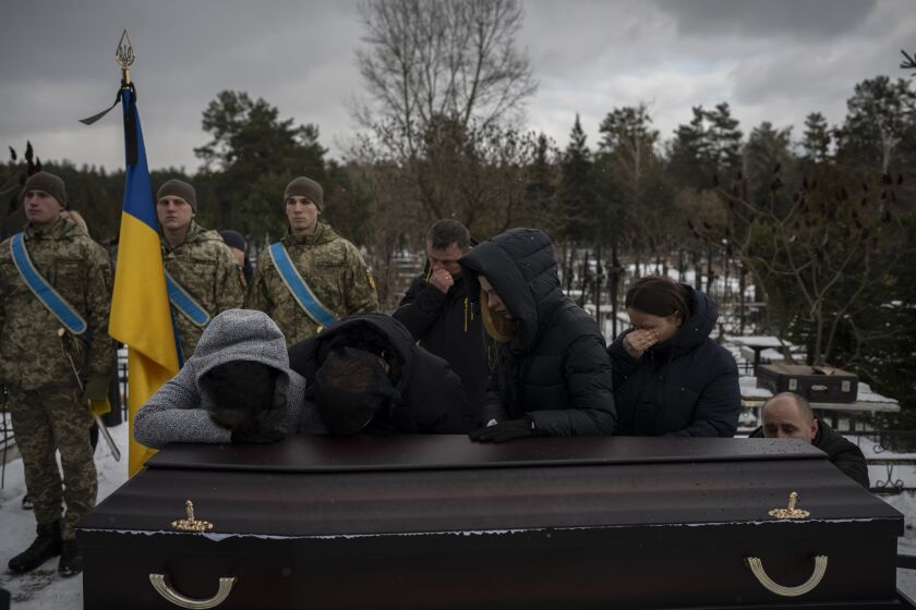 Relatives stand by the coffin of Eduard Strauss, a Ukrainian serviceman who died in combat on Jan. 17 in Bakhmut, during his funeral in Irpin, Ukraine, Monday, Feb. 6, 2023. (AP Photo/Daniel Cole)